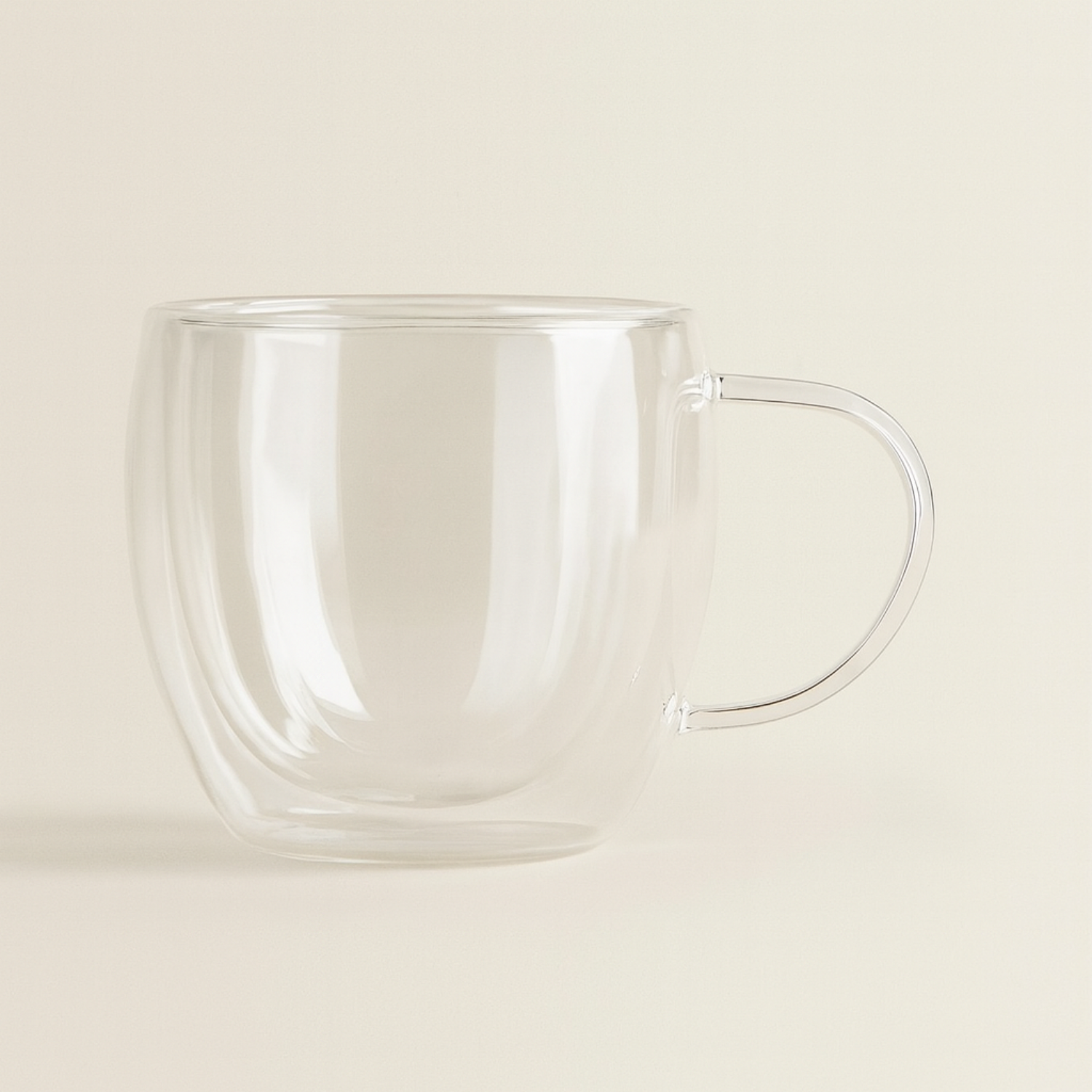 Clear glass mug with handle on a beige background
