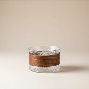 Glass candle holder with wooden band on a beige background