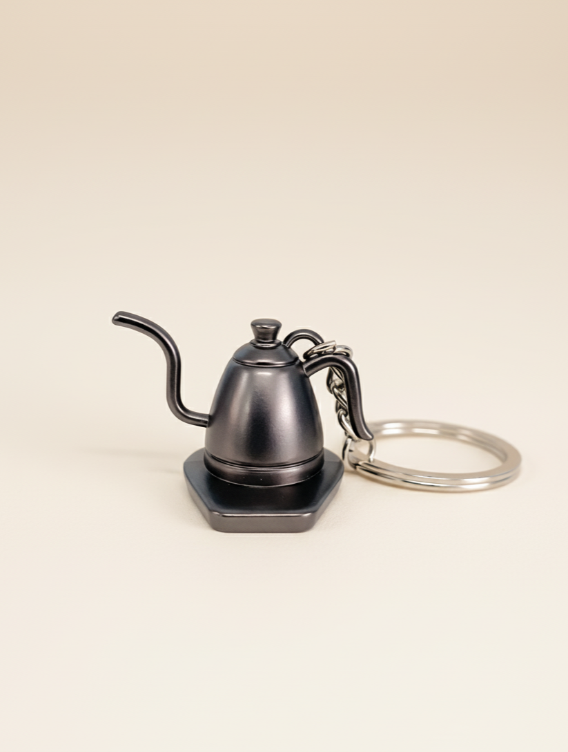 Keychain shaped like a coffee kettle on a beige background